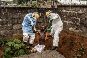 Ebola Virus for National Geographic Magazine. Medical staff at the Hastings Ebola Treatment Center escort a man in the throes of Ebola-induced delirium back into the isolation ward from which he escaped in Hastings, Sierra Leone, on Sunday, 23 November 2014. In a state of confusion, he emerged from the isolation ward and attempted to escape over the back wall of the complex before collapsing in a convulsive state. A complete breakdown of mental facilities is a common stage of advanced Ebola. The man pictured here died shortly after this picture was taken. © Pete Muller / Prime for National Geographic